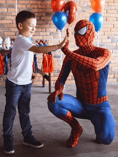 Animator Spider-Man îngenuncheat lângă un copil într-un spațiu de joacă.